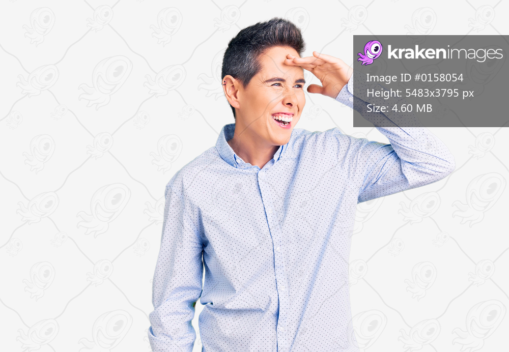 Young woman with short hair wearing business clothes very happy and smiling looking far away with hand over head. searching concept. 