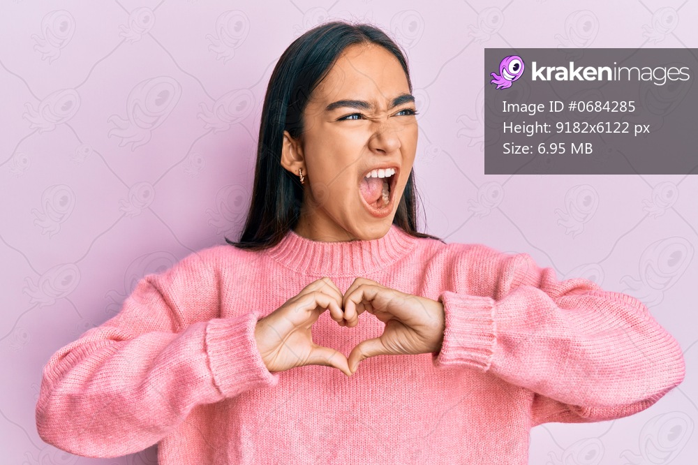 Young asian woman doing heart symbol with hands angry and mad screaming frustrated and furious, shouting with anger. rage and aggressive concept. 