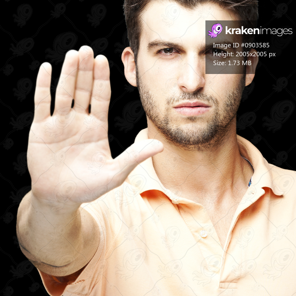 portrait of young man doing stop symbol over black background