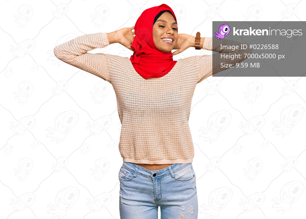 Young african american woman wearing traditional islamic hijab scarf relaxing and stretching, arms and hands behind head and neck smiling happy 