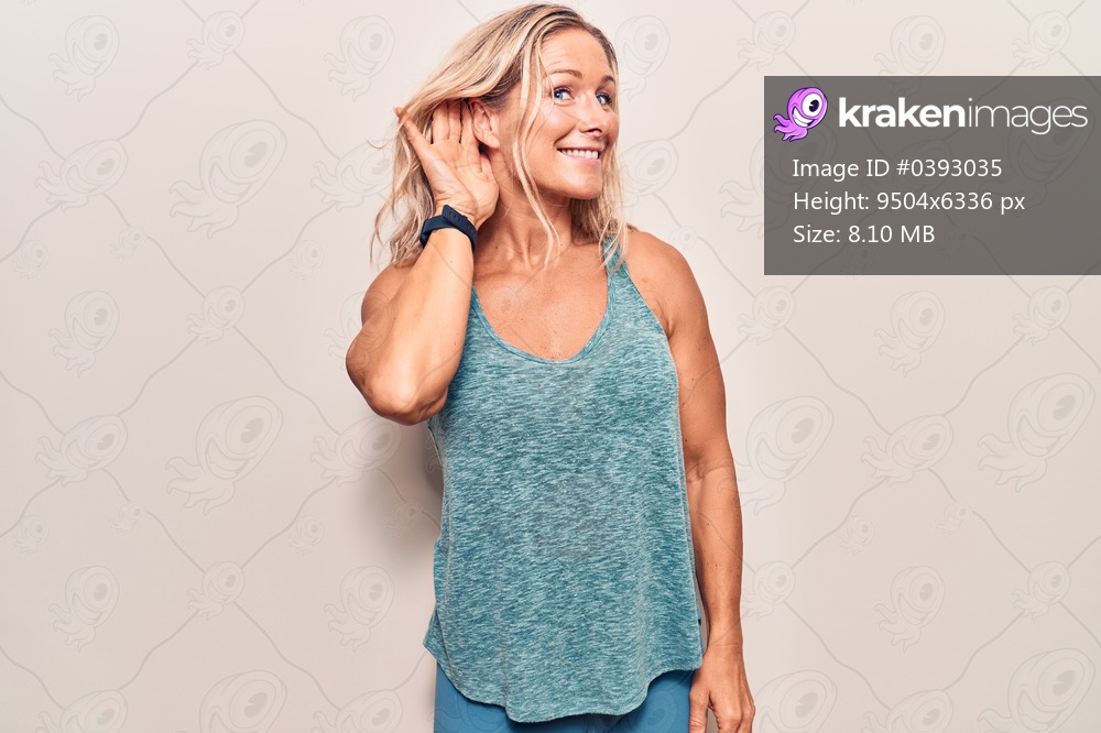 Middle age caucasian blonde woman wearing sportswear smiling with hand over ear listening an hearing to rumor or gossip. deafness concept. 