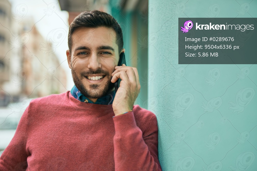 Young hispanic man smiling happy talking on the smartphone at the city.