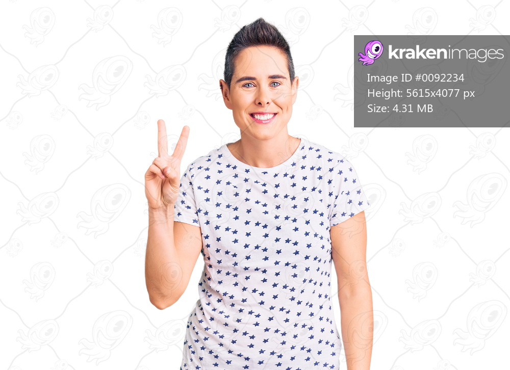 Young woman with short hair wearing casual clothes smiling with happy face winking at the camera doing victory sign. number two. 