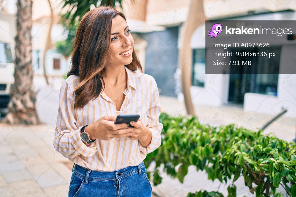 Young hispanic woman smiling happy using smartphone at the city.