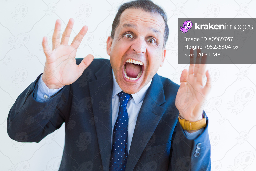 Middle age man shouting crazy with hands over mouth over white wall background