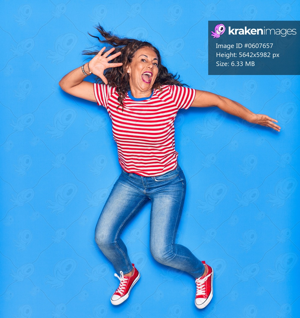 Middle age beautiful hispanic woman wearing casual clothes smiling happy. Jumping with smile on face over isolated blue background