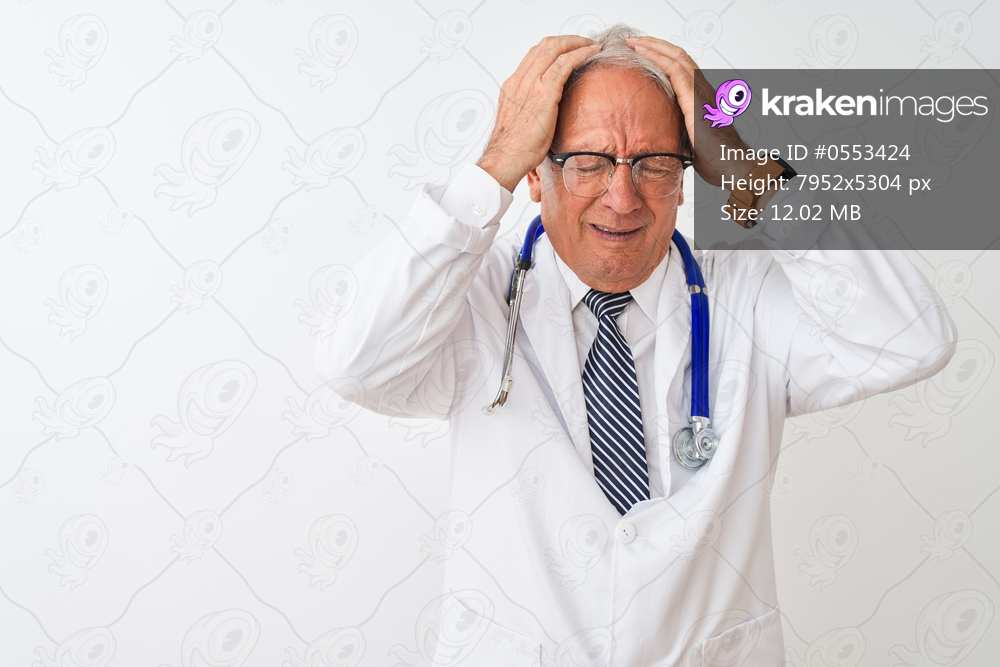 Senior grey-haired doctor man wearing stethoscope standing over isolated white background suffering from headache desperate and stressed because pain and migraine. Hands on head.