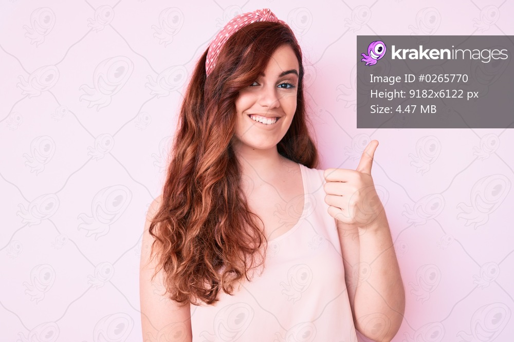Young beautiful woman wearing casual clothes doing happy thumbs up gesture with hand. approving expression looking at the camera showing success. 