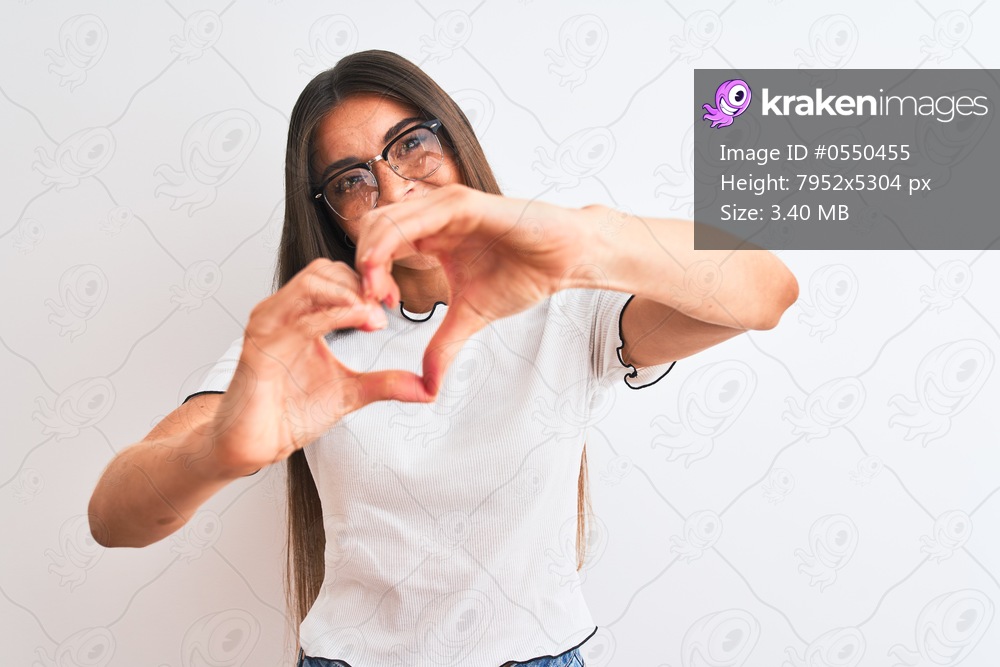Young beautiful woman wearing casual t-shirt and glasses over isolated white background smiling in love showing heart symbol and shape with hands. Romantic concept.