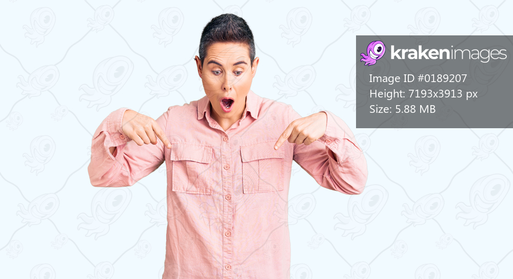 Young woman with short hair wearing casual clothes pointing down with fingers showing advertisement, surprised face and open mouth 