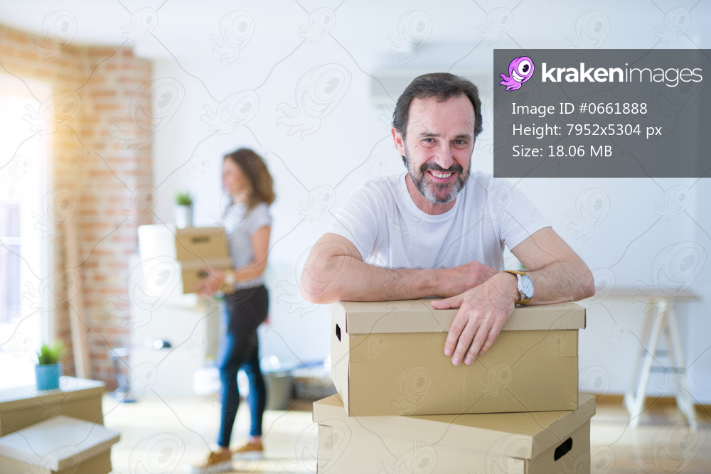 Middle age senior couple moving to a new house, man smiling happy in love with new apartment