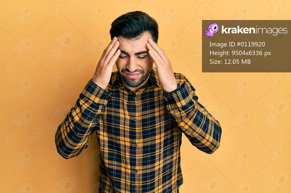 Young hispanic man wearing casual clothes with hand on head, headache because stress. suffering migraine. 