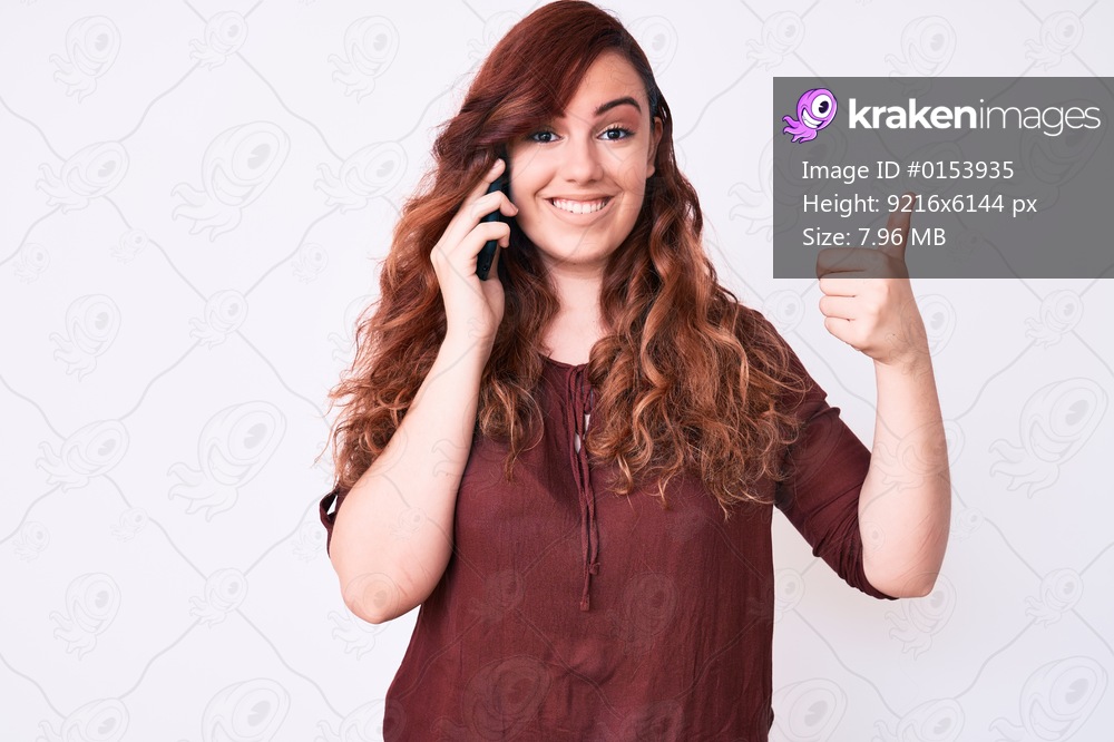 Young beautiful woman having conversation talking on the smartphone smiling happy and positive, thumb up doing excellent and approval sign 