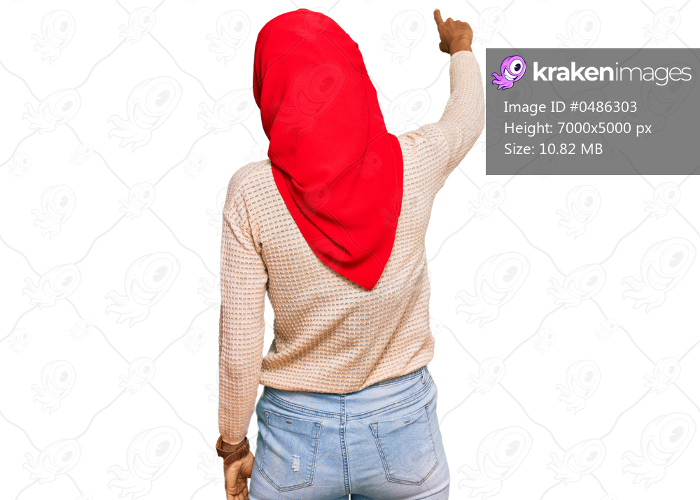 Young african american woman wearing traditional islamic hijab scarf posing backwards pointing ahead with finger hand 