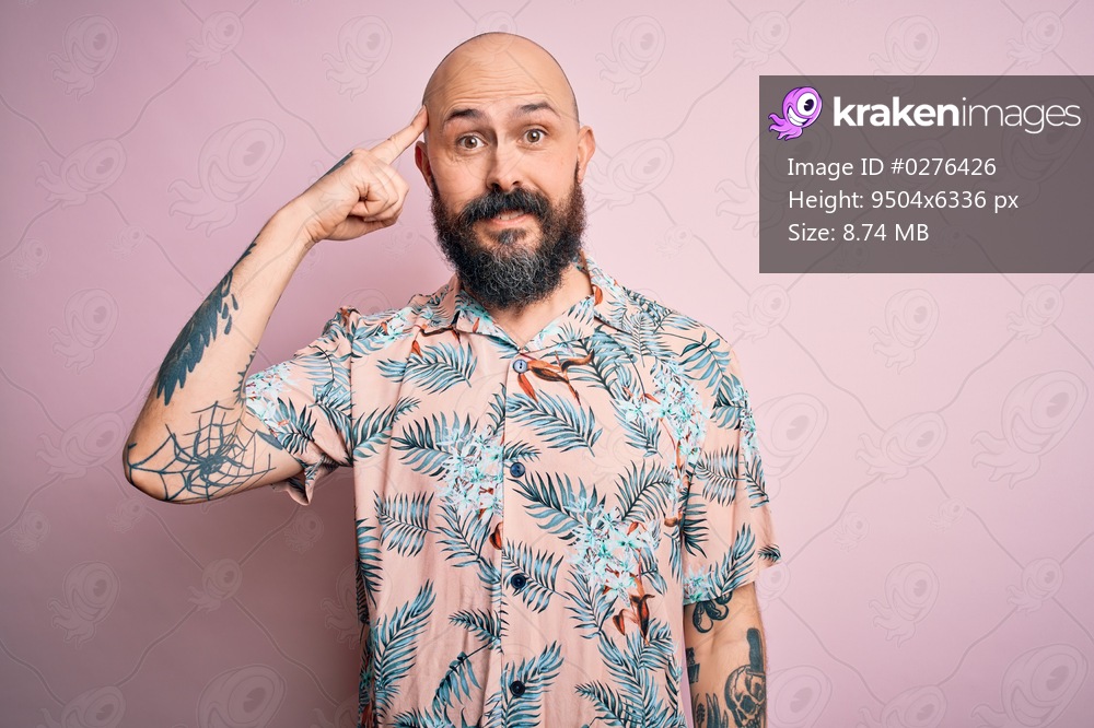 Handsome bald man with beard and tattoo wearing casual floral shirt over pink background Smiling pointing to head with one finger, great idea or thought, good memory