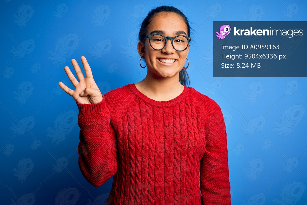 Young beautiful asian woman wearing casual sweater and glasses over blue background showing and pointing up with fingers number four while smiling confident and happy.