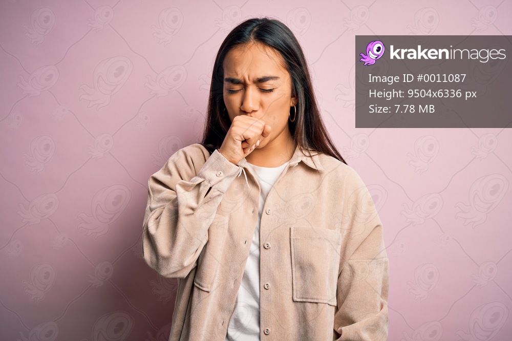 Young beautiful asian woman wearing casual shirt standing over pink background feeling unwell and coughing as symptom for cold or bronchitis. Health care concept.