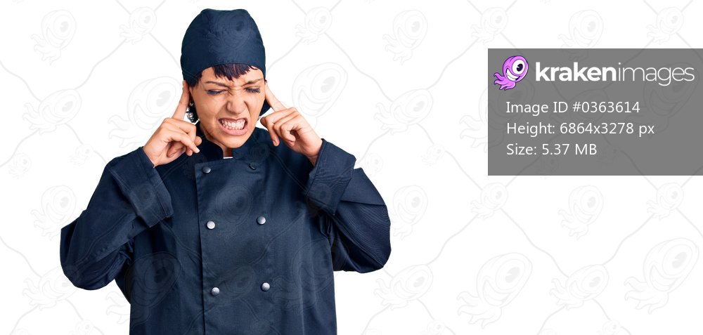 Young brunette woman with short hair wearing professional cook uniform covering ears with fingers with annoyed expression for the noise of loud music. deaf concept. 