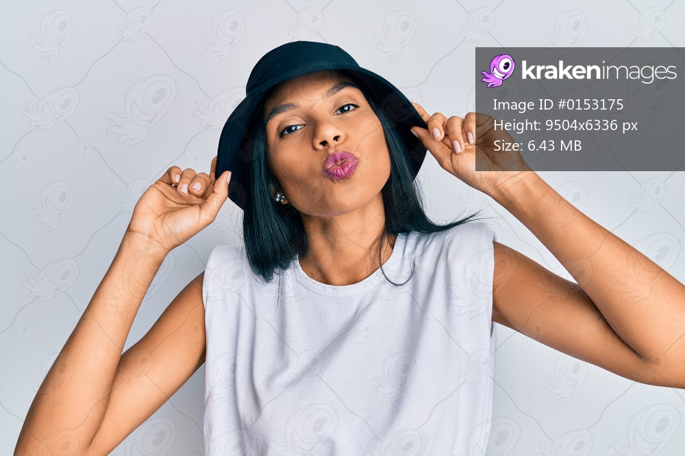 Young african american woman wearing fashion hat looking at the camera blowing a kiss being lovely and sexy. love expression. 