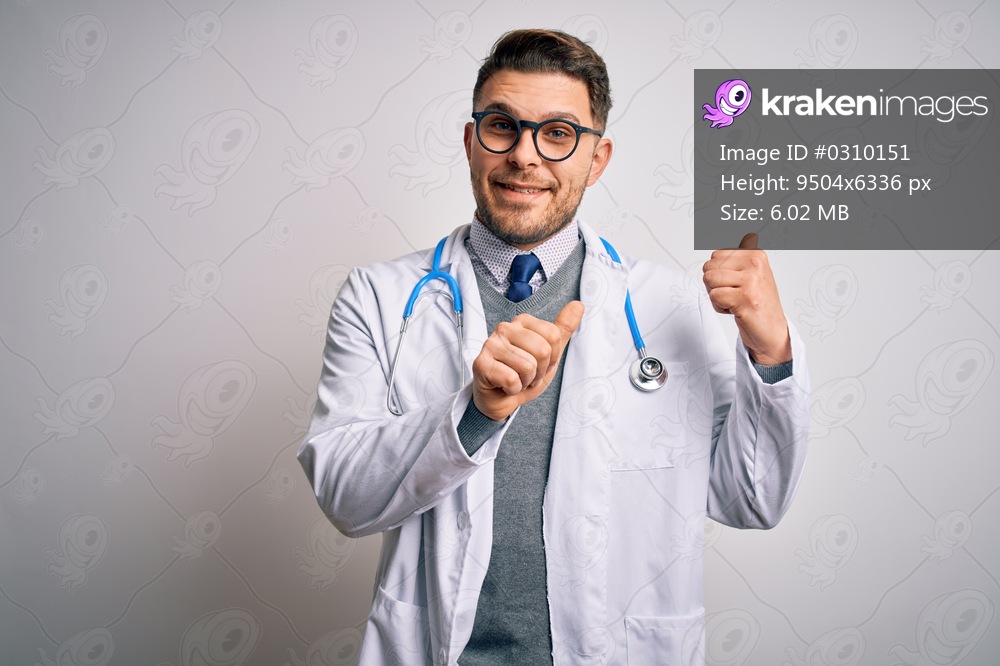 Young doctor man with blue eyes wearing medical coat and stethoscope over isolated background Pointing to the back behind with hand and thumbs up, smiling confident