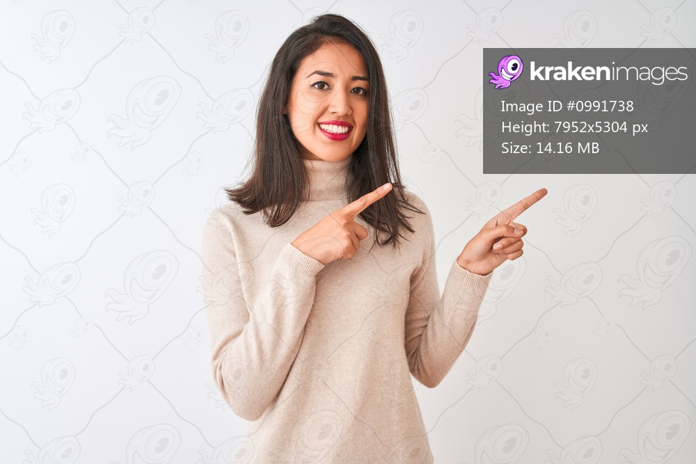 Beautiful chinese woman wearing turtleneck sweater standing over isolated white background smiling and looking at the camera pointing with two hands and fingers to the side.