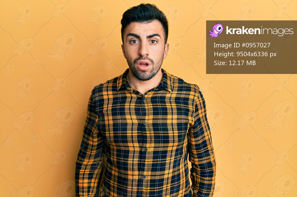 Young hispanic man wearing casual clothes in shock face, looking skeptical and sarcastic, surprised with open mouth 