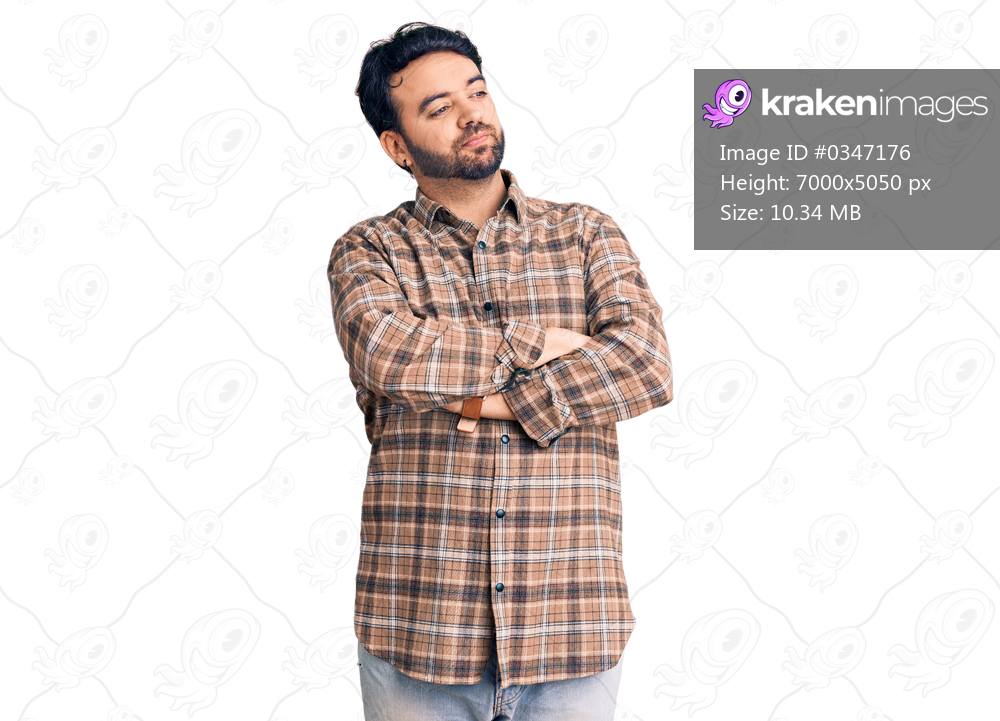 Young hispanic man wearing casual clothes looking to the side with arms crossed convinced and confident 