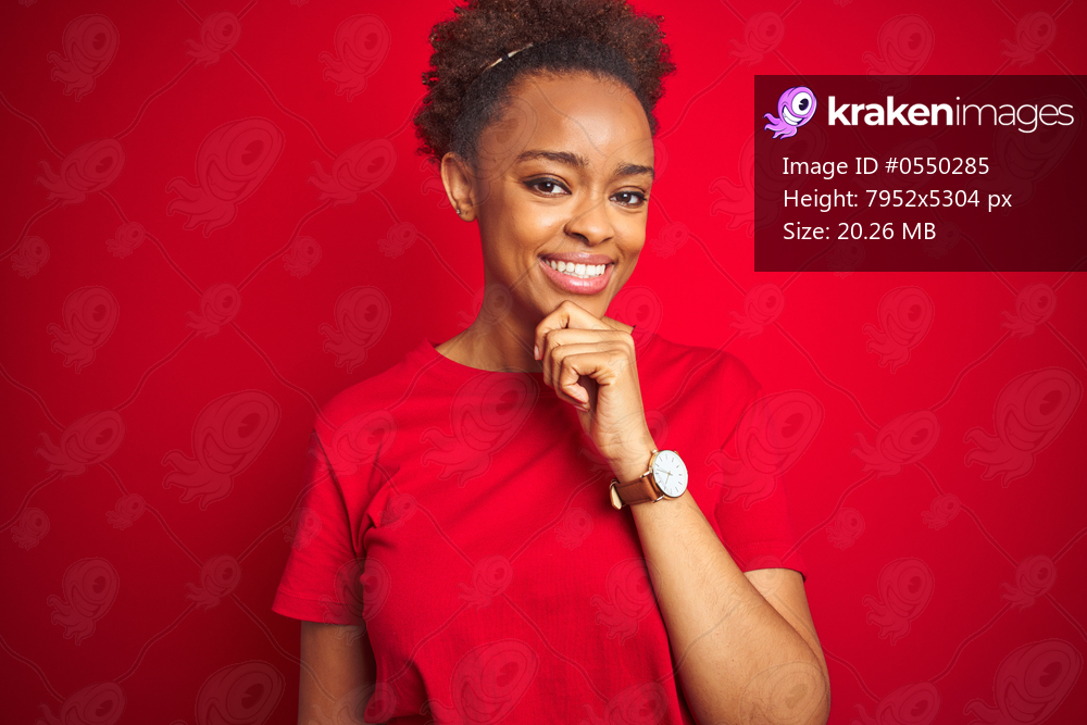 Young beautiful african american woman with afro hair over isolated red background with hand on chin thinking about question, pensive expression. Smiling and thoughtful face. Doubt concept.