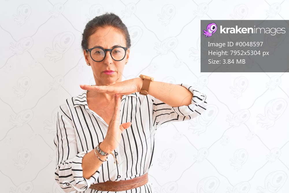Middle age businesswoman wearing striped dress and glasses over isolated white background Doing time out gesture with hands, frustrated and serious face