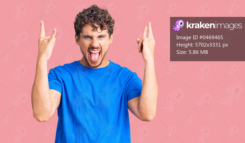 Young handsome man with curly hair wearing casual clothes shouting with crazy expression doing rock symbol with hands up. music star. heavy music concept. 