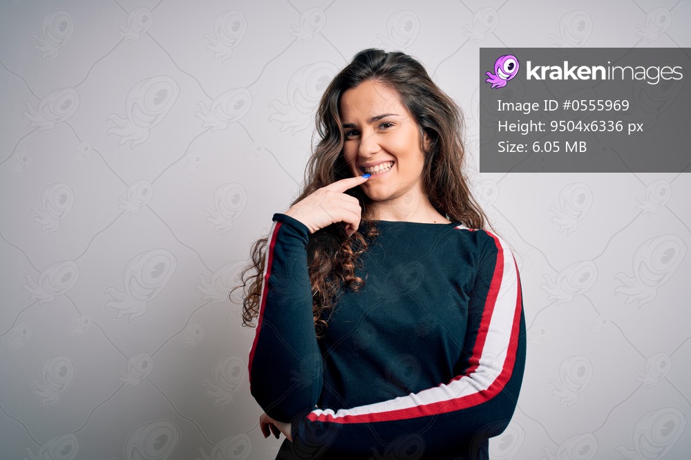 Young beautiful woman with curly hair wearing casual sweater over isolated white background looking confident at the camera with smile with crossed arms and hand raised on chin. Thinking positive.