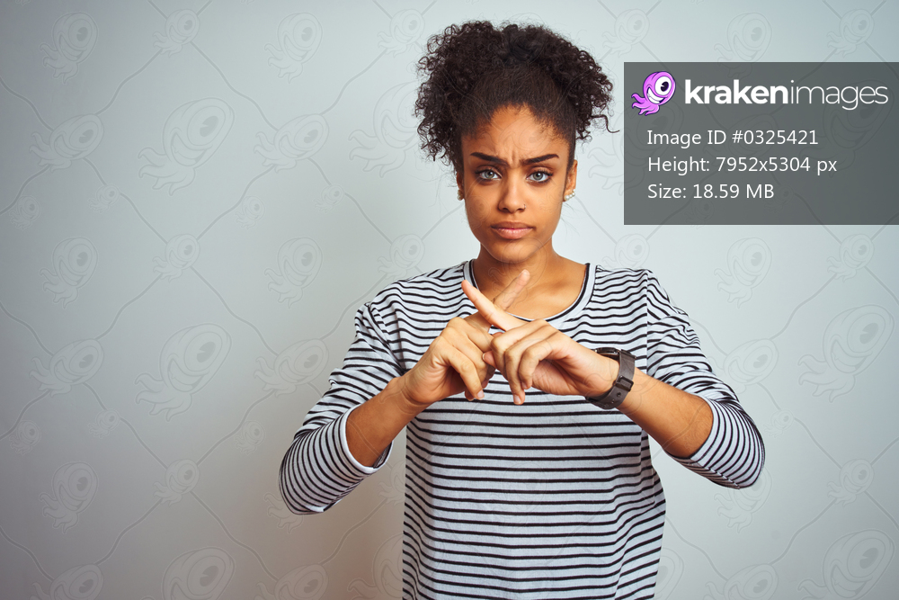 African american woman wearing navy striped t-shirt standing over isolated white background Rejection expression crossing fingers doing negative sign