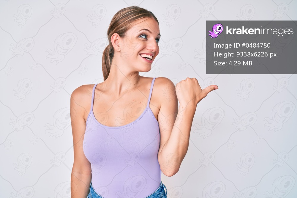 Young blonde girl wearing casual style with sleeveless shirt pointing thumb up to the side smiling happy with open mouth 