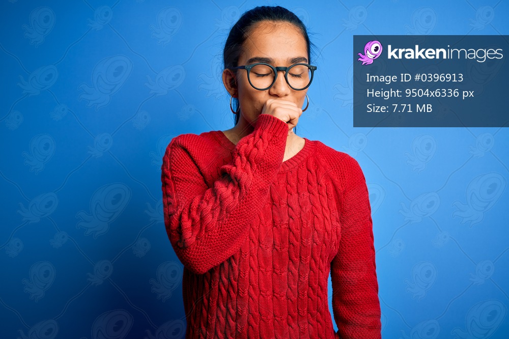 Young beautiful asian woman wearing casual sweater and glasses over blue background feeling unwell and coughing as symptom for cold or bronchitis. Health care concept.