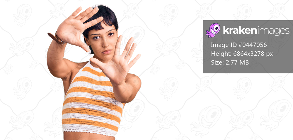 Young brunette woman with short hair wearing casual clothes doing frame using hands palms and fingers, camera perspective 