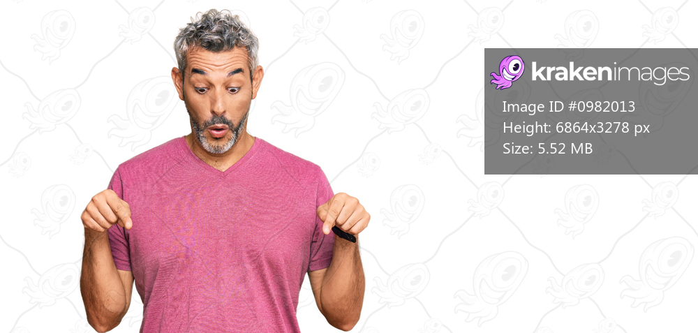 Middle age grey-haired man wearing casual clothes pointing down with fingers showing advertisement, surprised face and open mouth 