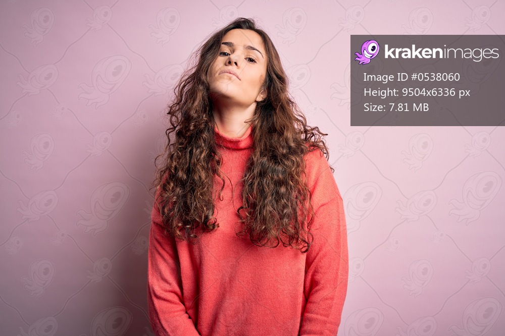 Young beautiful woman with curly hair wearing turtleneck sweater over pink background Relaxed with serious expression on face. Simple and natural looking at the camera.