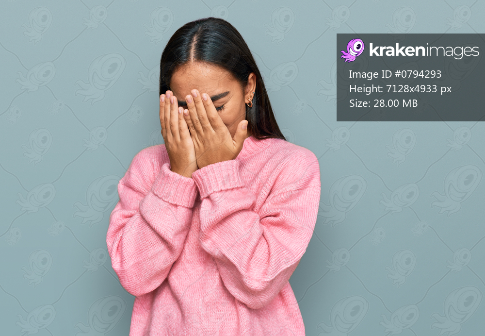 Young asian woman wearing casual winter sweater with sad expression covering face with hands while crying. depression concept. 