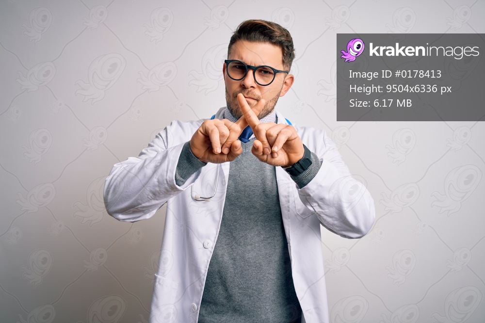 Young doctor man with blue eyes wearing medical coat and stethoscope over isolated background Rejection expression crossing fingers doing negative sign