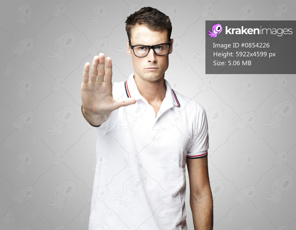portrait of a handsome young man doing stop symbol over black background