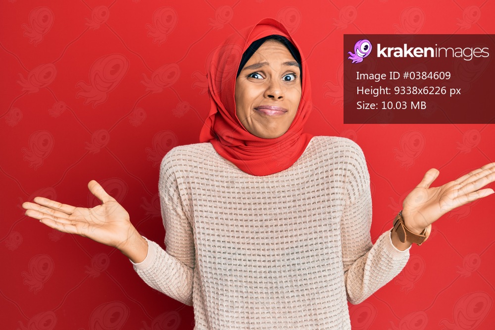 Young african american woman wearing traditional islamic hijab scarf clueless and confused with open arms, no idea and doubtful face. 