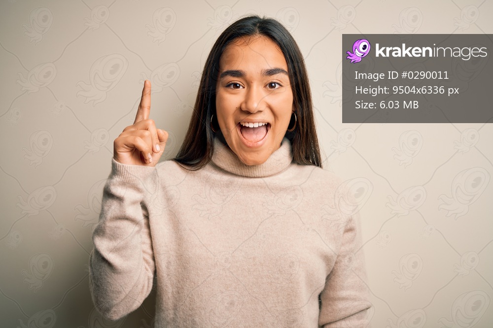 Young beautiful asian woman wearing casual turtleneck sweater over white background pointing finger up with successful idea. Exited and happy. Number one.