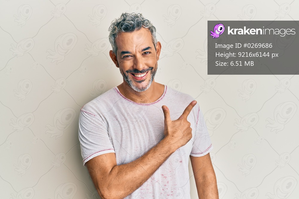 Middle age grey-haired man wearing casual clothes cheerful with a smile of face pointing with hand and finger up to the side with happy and natural expression on face 