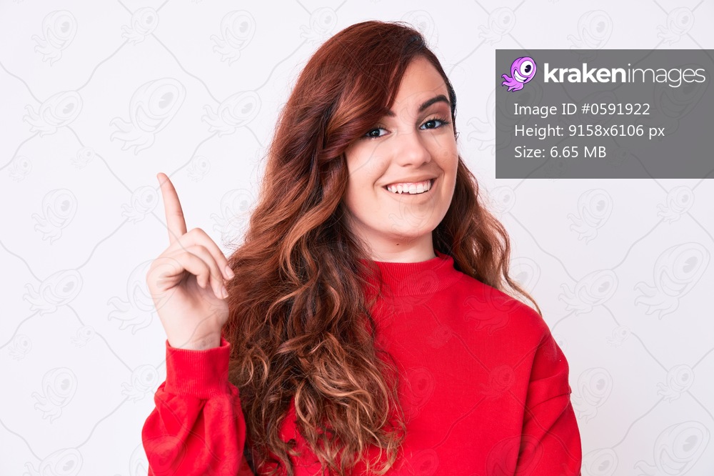 Young beautiful woman wearing casual clothes with a big smile on face, pointing with hand and finger to the side looking at the camera. 