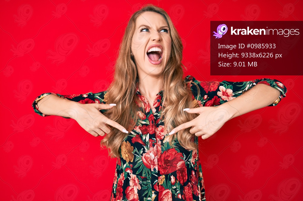 Young caucasian woman with blond hair pointing with fingers to herself angry and mad screaming frustrated and furious, shouting with anger. rage and aggressive concept. 