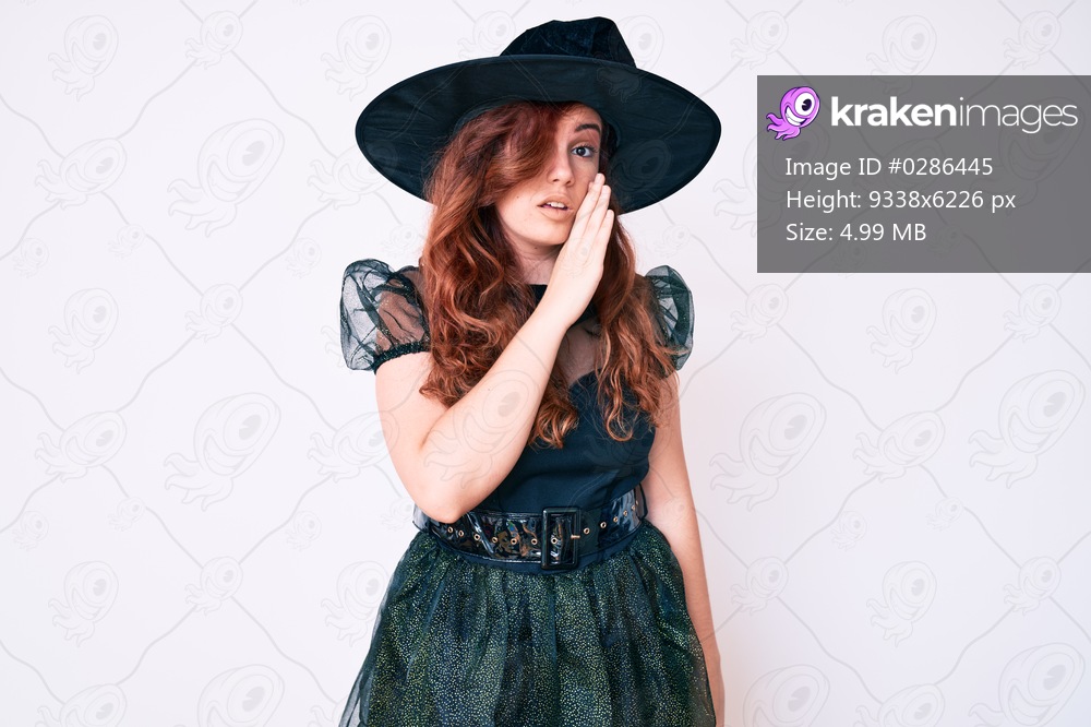 Young beautiful woman wearing witch halloween costume hand on mouth telling secret rumor, whispering malicious talk conversation 