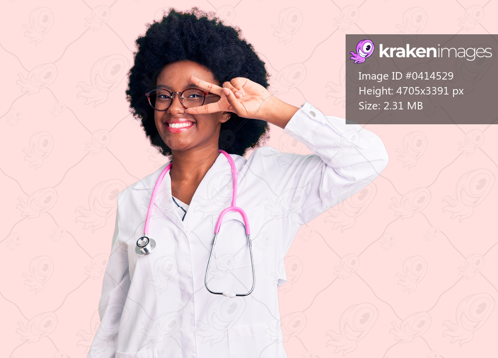 Young african american woman wearing doctor coat and stethoscope doing peace symbol with fingers over face, smiling cheerful showing victory 