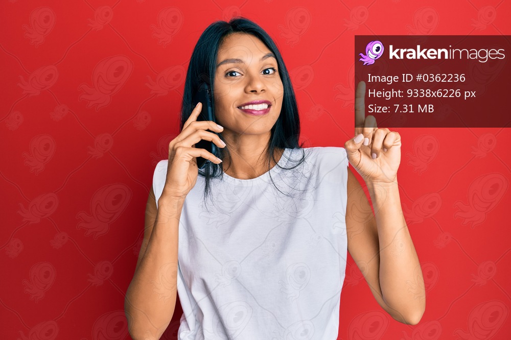 Young african american woman having conversation talking on the smartphone smiling with an idea or question pointing finger with happy face, number one 