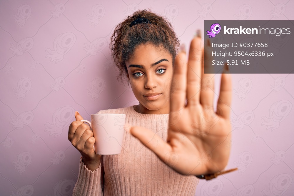 Young african american afro girl drinking cup of coffee over isolated pink background with open hand doing stop sign with serious and confident expression, defense gesture