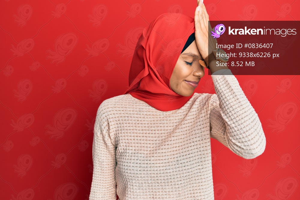 Young african american woman wearing traditional islamic hijab scarf surprised with hand on head for mistake, remember error. forgot, bad memory concept. 
